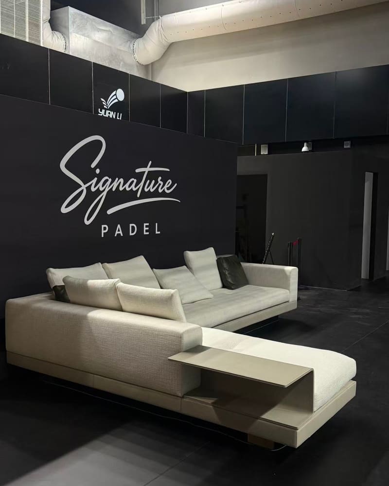 Lounge with a white sofa in front of the Signature Padel wall logo